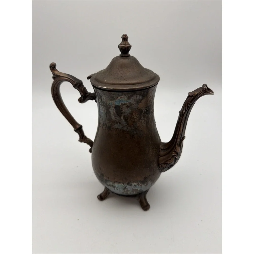 vintage silver-plated footed coffee or teapot features an ornate handle,